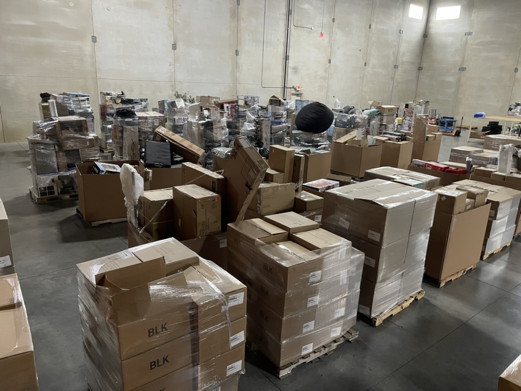 Warehouse floor packed with pallets of shrink-wrapped boxes of liquidation merchandise